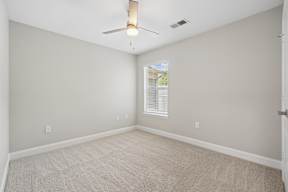 A room with a ceiling fan and carpeted floor.