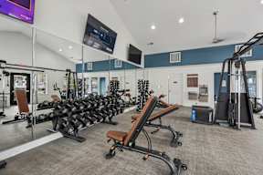 A gym with a variety of equipment including weights and cardio machines.