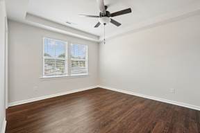A room with a ceiling fan and wooden flooring.