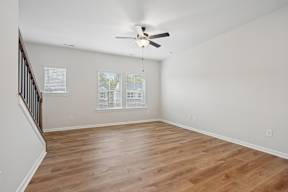 A room with a ceiling fan and wooden flooring.