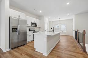 A kitchen with a refrigerator, microwave, oven, and sink.