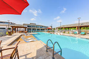 A large outdoor swimming pool with a red umbrella.