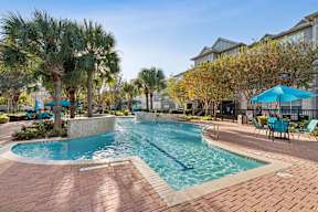 A swimming pool surrounded by palm trees and lounge chairs.