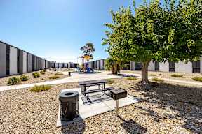 a playground with a picnic table and a tree in front of a building