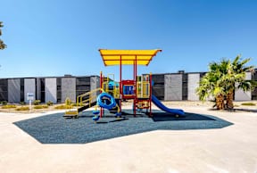 a colorful playground in front of a building with palm trees