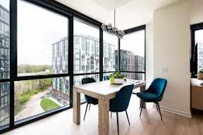 A modern dining room with a table and chairs and a view of a cityscape through the windows.