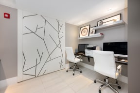 a white office with two white chairs and a desk with a monitor