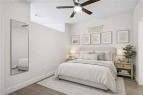 A bedroom with a bed, a ceiling fan, and a mirror.