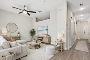A living room with a white couch, a coffee table, and a ceiling fan.