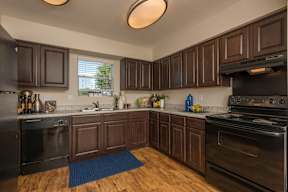 A kitchen with dark wood cabinets and black appliances.