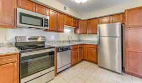 A kitchen with brown cabinets, light countertops, and stainless steel appliances.