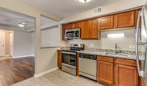 A kitchen with brown cabinets, light countertops, and stainless steel appliances.