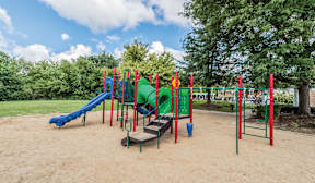 A playground with a blue slide and red and green climbing structures.