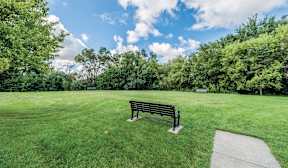 A park bench sits in the middle of a grassy field.