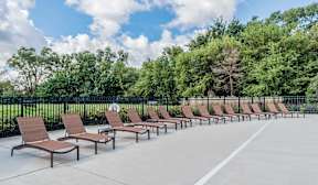 A row of brown lounge chairs are set up on a concrete patio.