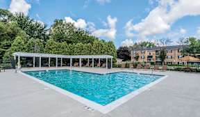 A large outdoor swimming pool with a white fence around it.