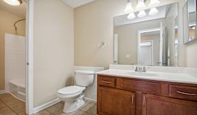 A white toilet sits in a bathroom next to a sink.