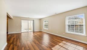 A room with wooden floors and a window with blinds.