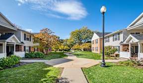 A street view of a residential area with houses on both sides and a sidewalk in the middle.