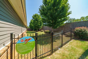 a yard with a fence with a sign on it