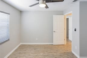 an empty room with a white door and a ceiling fan