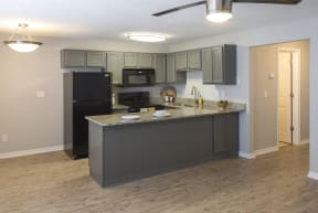 a kitchen with an island and a black refrigerator