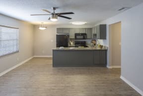 an empty kitchen and living room with a ceiling fan