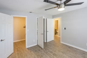 an empty bedroom with a ceiling fan and a door to a closet
