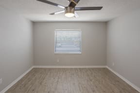 an empty room with a ceiling fan and a window