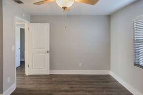 an empty living room with a white door and a ceiling fan