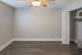 an empty living room with a ceiling fan and a closet
