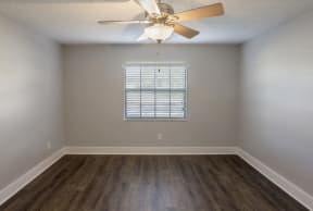 an empty room with wooden floors and a ceiling fan