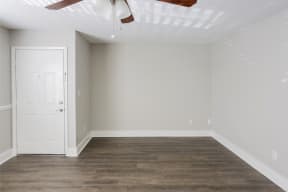 an empty living room with wood floors and a white door