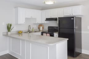 a kitchen with white cabinets and a large island with a black refrigerator