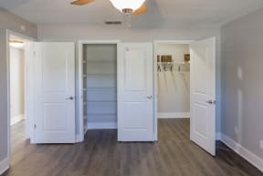 an empty closet with white doors and a mirrored closet door