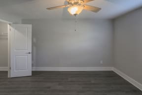 an empty living room with a ceiling fan and a white door