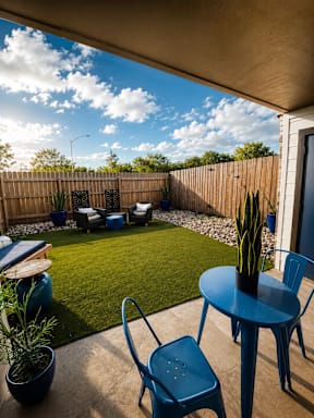 A blue chair sits on a patio with a table and a potted plant.