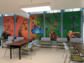 A room with a long table and chairs with a mural on the wall.