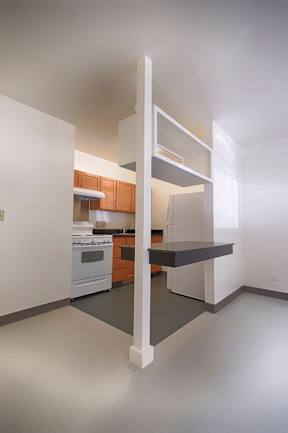 A kitchen with a white wall and a white floor with a white oven and a white fridge.