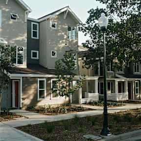 A street lamp stands in front of a house with a red door.