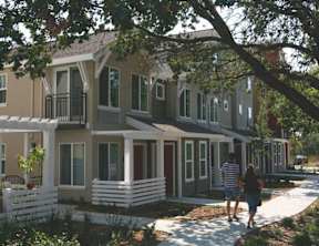 A couple walking in front of a row of houses.