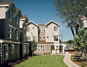 A row of houses with a green lawn in front.