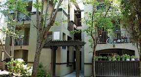A building with a balcony and a tree in front of it.