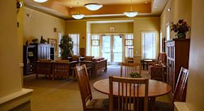 A room with a table and chairs in the foreground and a doorway in the background.