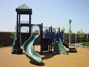 A playground with a green slide and a blue tower.