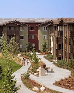 A group of people walking down a path in a courtyard surrounded by buildings.