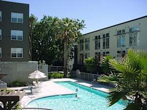 A pool surrounded by palm trees and buildings.