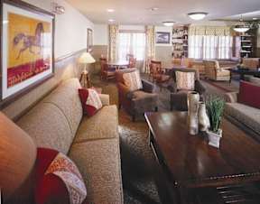 A living room with a brown couch and a painting of a horse on the wall.