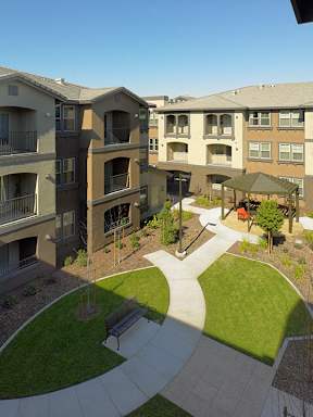 Apartment complex with a green lawn and a walkway.
