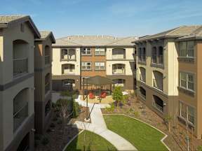 Apartment complex with a green lawn and trees in the courtyard.